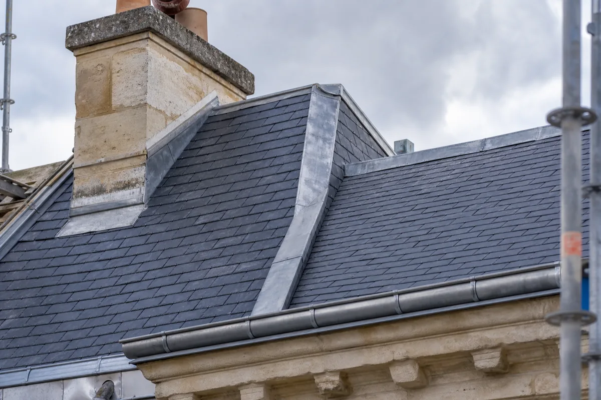 Détail d’une toiture en ardoise à combles brisés avec zinguerie en zinc mat
