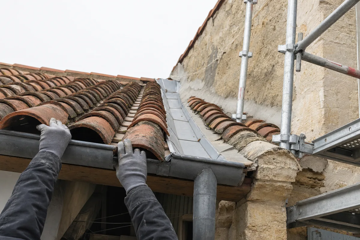 Chéneau en zinc et rive de toiture entre deux maisons mitoyennes en pierre calcaire blonde